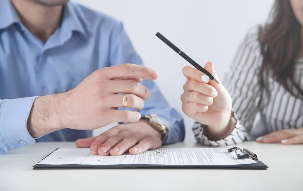 Woman passes a pen to a man for signing divorce papers