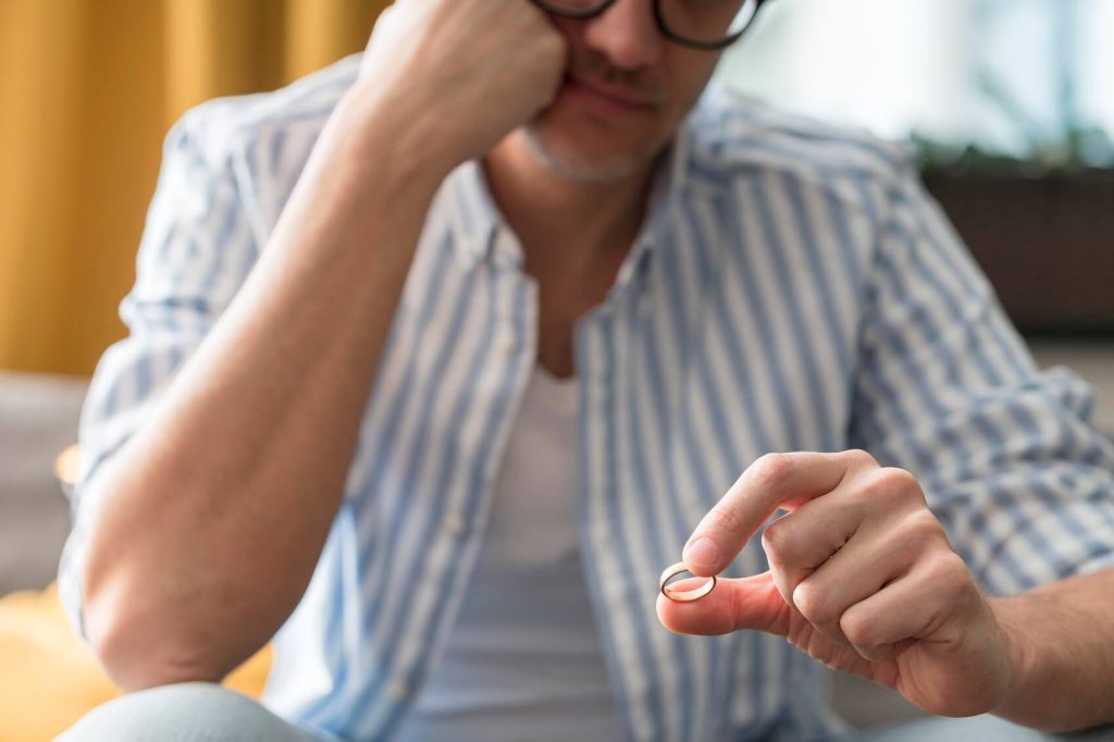 Man considering divorce while holding wedding ring